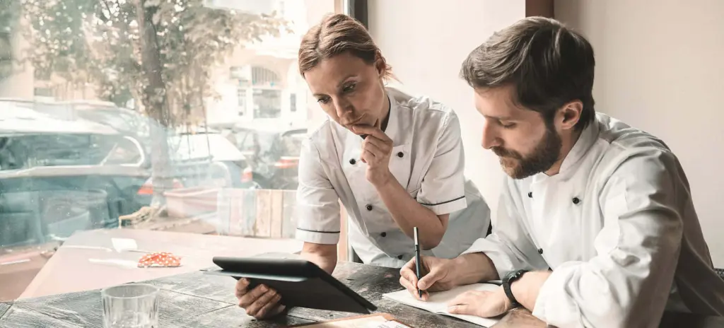 Zwei Köche stehen beieinander und unterhalten sich.