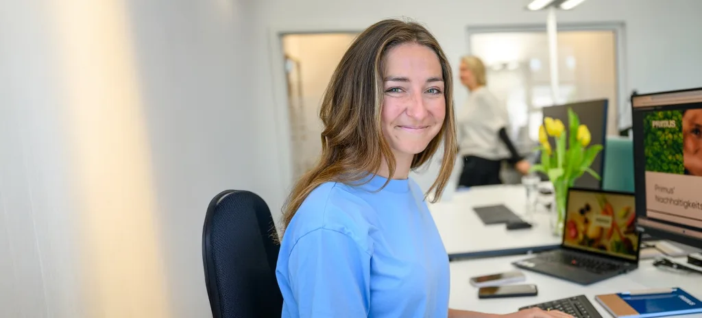 Eine lächelnde Frau sitzt in einem Büro.