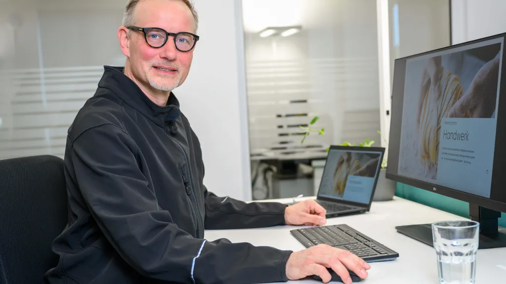 Ein Mitarbeiter sitzt an einem Schreibtisch in einem Büro.