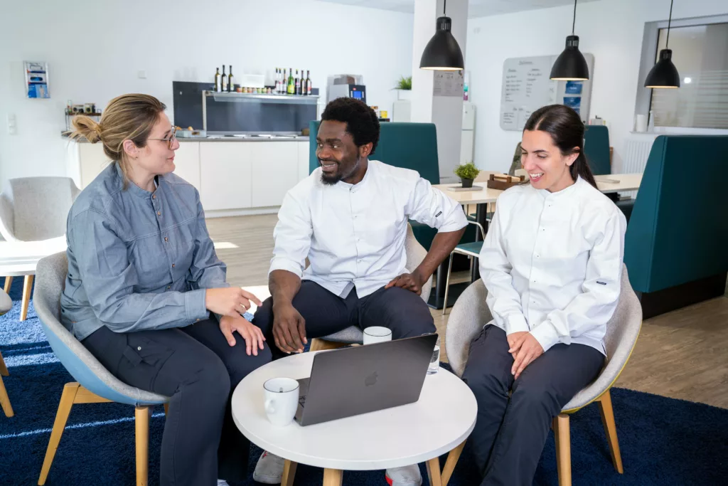 Drei Küchenmitarbeiter sitzen gemeinsam an einem Tisch.