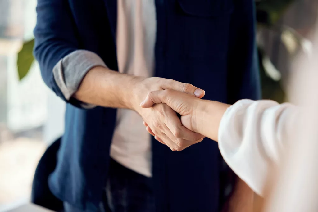 Zwei Personen geben sich die Hand.