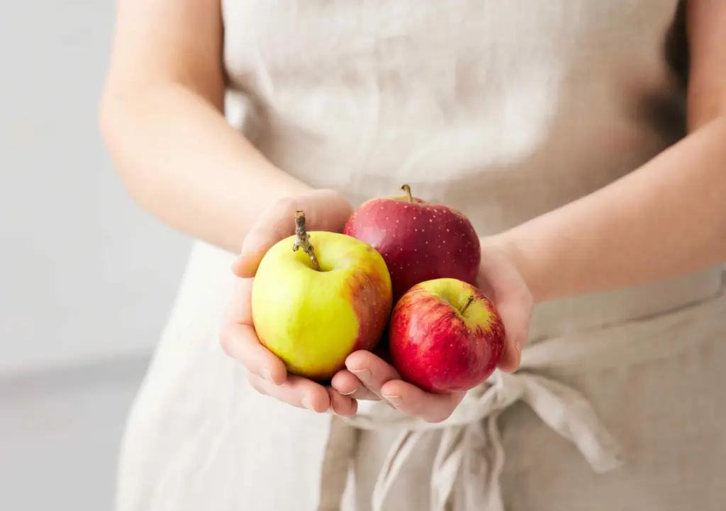 Zwei Hände halten mehrere frische Äpfel.
