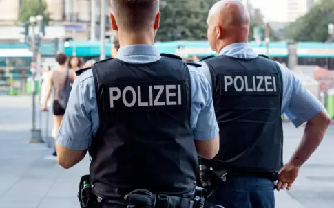 Zwei Polizisten stehen auf einem öffentlichen Platz.