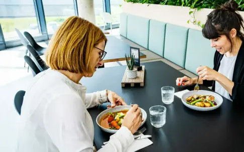 Zwei Frauen befinden sich in einer Kantine.